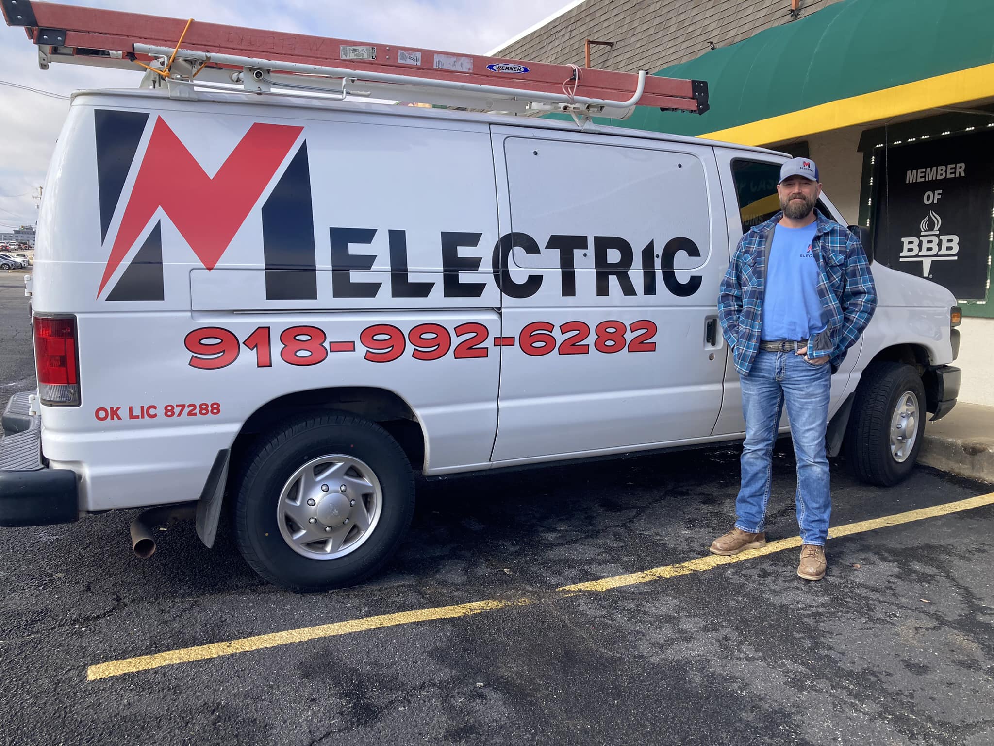 Marshall Morgan, owner and master electrician of M Electric, LLC, standing beside the M Electric service van outside the BBB-accredited Tulsa business location